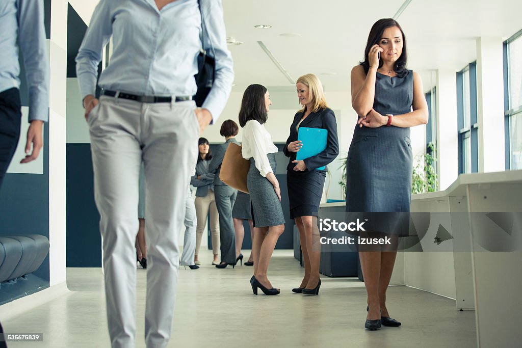 Group of businesswomen in an office corridor Group of businesswomen having break during conference, standing in the hall in modern office. Woman on the right site talking on phone. 2015 Stock Photo