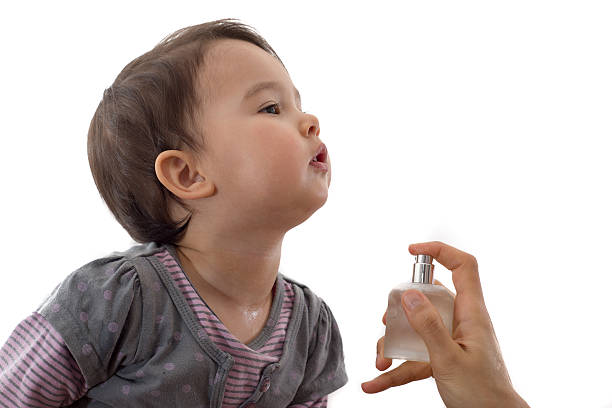 Little girl being scented by her mother stock photo