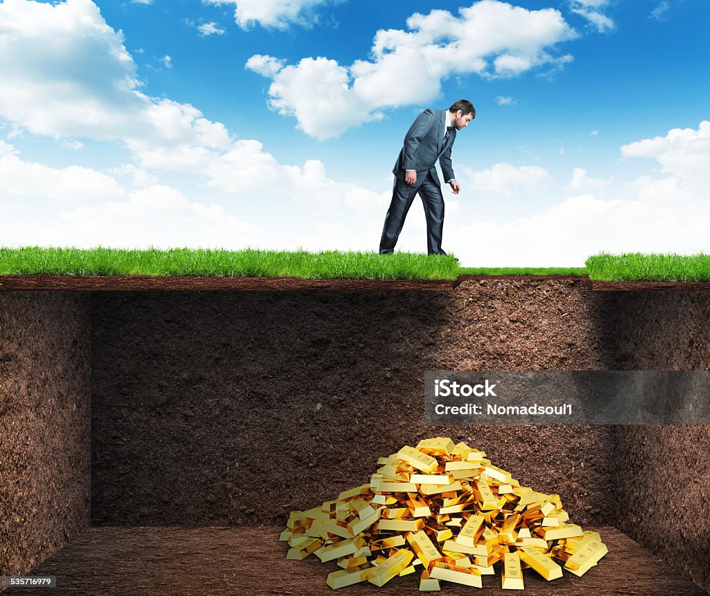 Businessman found treasure in the soil Businessman bends and looks at the treasure in the soil Treasure Chest Stock Photo