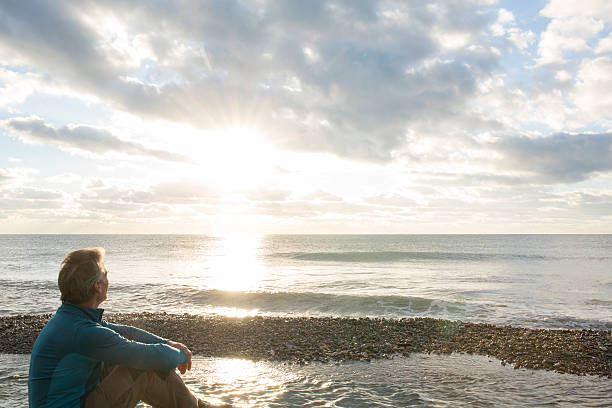 istock Man faces out to sea at sunrise, contemplative 535721707