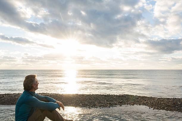 istock Man faces out to sea at sunrise, contemplative 535721709