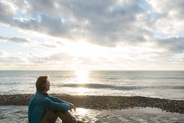 istock Man faces out to sea at sunrise, contemplative 535721711
