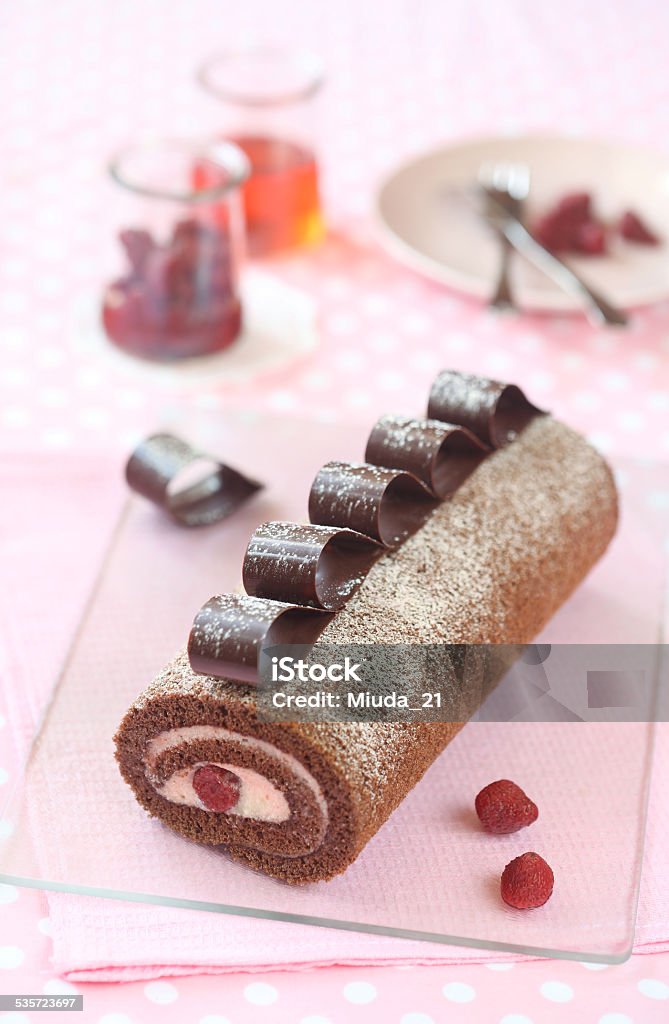 Chocolate Strawberry Swiss Roll Cake Chocolate Strawberry Swiss Roll Cake decorated with chocolate loops on a pink napkin and light pink background. Yule Log Stock Photo