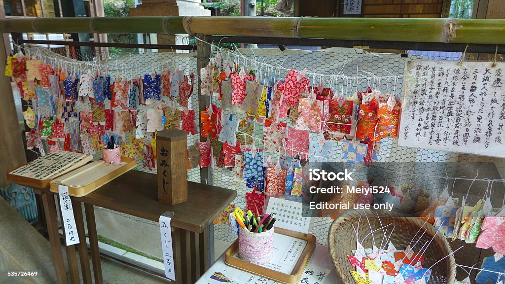 Omikuji (Fortune Paper), Kyoto, Japan Kyoto, Japan - October 28, 2014: Full of colourful clothes shaped Omikuji (Fortune Papers) are tied on the strings of a wooden shelf inside of Fushimi Inari Taisha (Shrine). People believe that it will brings lucks to them. Took in a sunny morning in autumn.  2015 Stock Photo