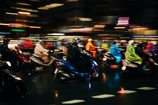 Scooters at a busy road junction, blurred by motion, night time. Taipei, Taiwan. 