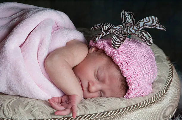 Photo of Newborn Baby girl sleeping wrapped in pink