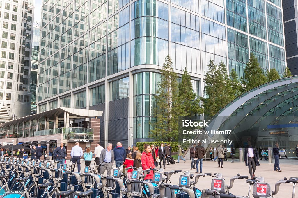 Canary Wharf district with Barclays Cycle Hire docking station London, United Kingdom - October 30, 2013: Canary Wharf district with Barclays Cycle Hire docking station and Underground entrance. Many people, tourists and commuters, are walking in the square. 2015 Stock Photo
