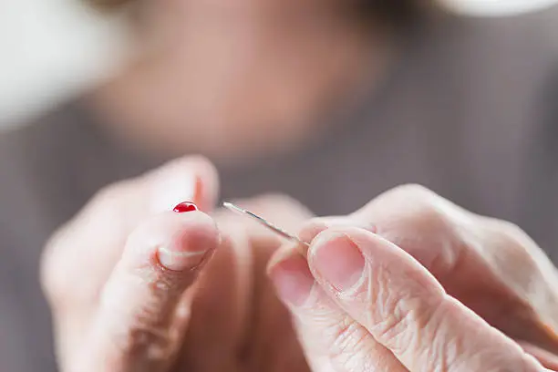 A diabetic testing her blood sugar.  Close-up of the fingers of a senior woman with a drop of blood.
