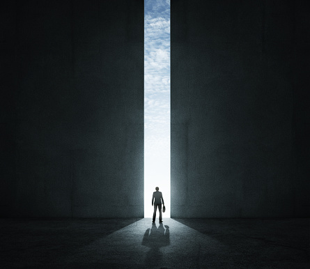 Silhouette of a businessman standing by the huge open gate