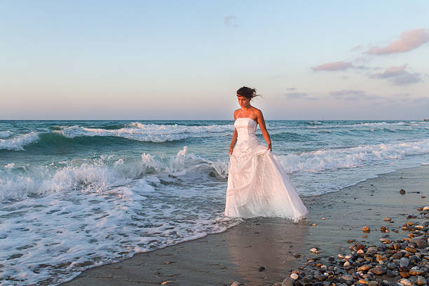 istock Young bride enjoys a walk at the beach at dusk. 535770505