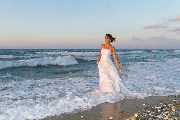 istock Young bride enjoys a walk at the beach at dusk. 535770507
