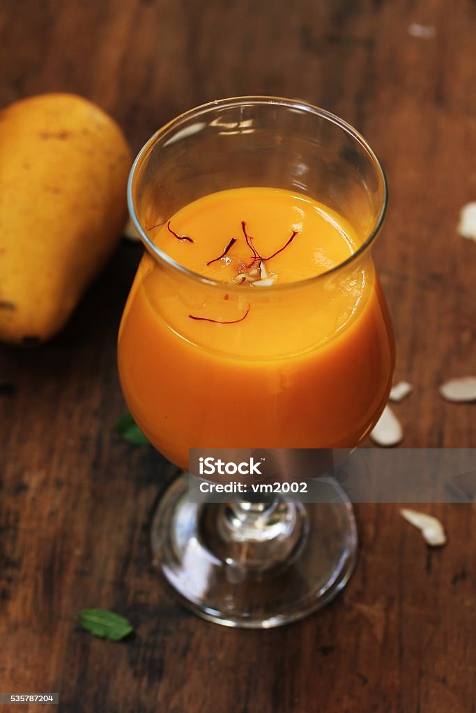 Mango Lassi  with Saffron garnish on wooden background Mango Lassi  with Saffron garnish on wooden background, selective focus Lassi - Drink Stock Photo