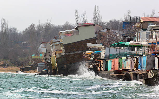 Coastal erosion, houses slide down to sea stock photo