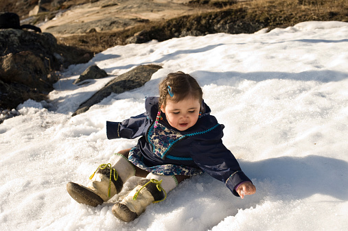 Boy sliding down snowy hill on toboggan