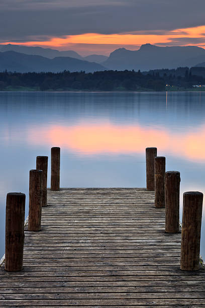 Langdales Over Windermere A wooden jetty over looking Windermere at sunset with the Langdale Pikes in the distance langdale pikes stock pictures, royalty-free photos & images