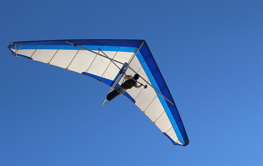 Hang Glider flying in the sky on a bright blue day