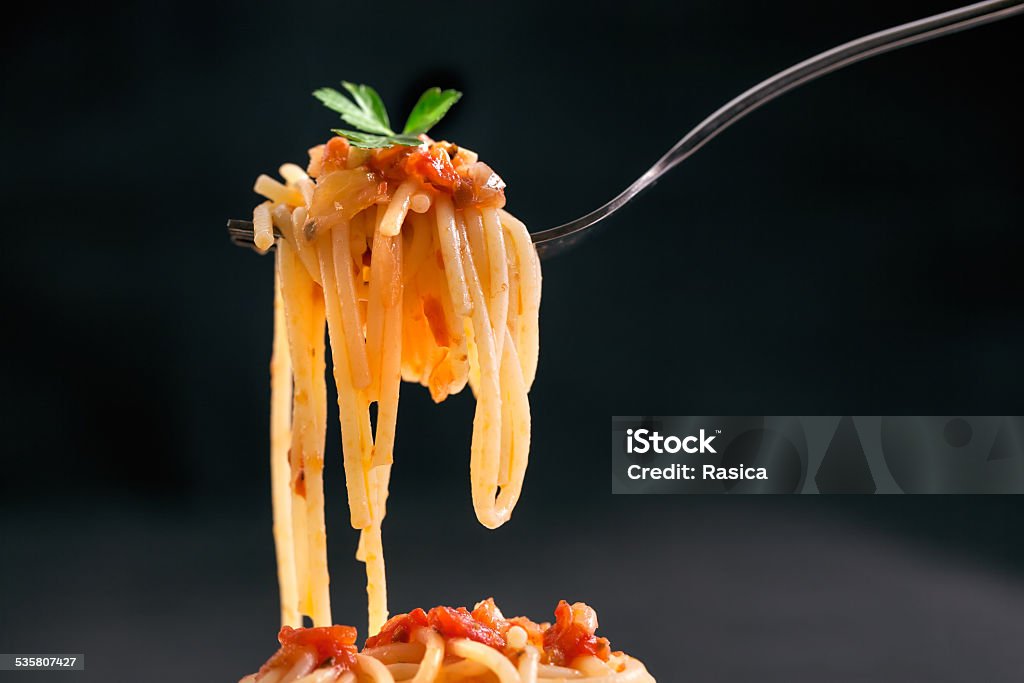 Fresh hot spaghetti wrapped on fork Fresh bite of hot spaghetti wrapped on fork against the dark black background. Shallow depth of field. 2015 Stock Photo