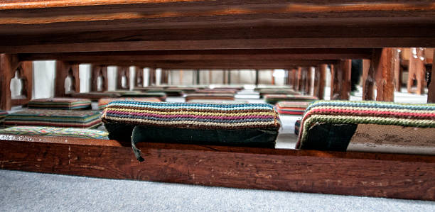 Rear view color image depicting a Jewish man in his 30s, wearing a skull cap embroidered with the Star of David, praying alone inside the synagogue. Focus on the man with the place of worship defocused beyond. Room for copy space.