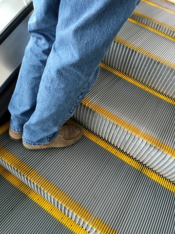 man wearing jeans on escalator steps