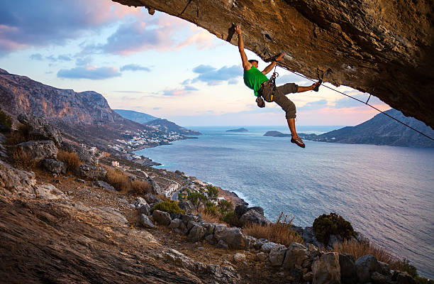 alpinista macho escalada saliente cliff - climbing men sea cliff imagens e fotografias de stock