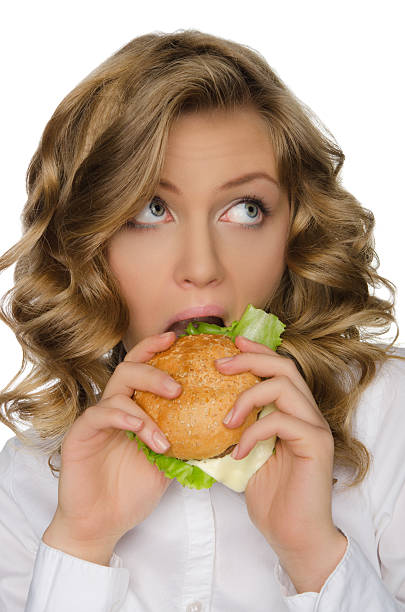 istock Young woman biting burger and looking away 535812077