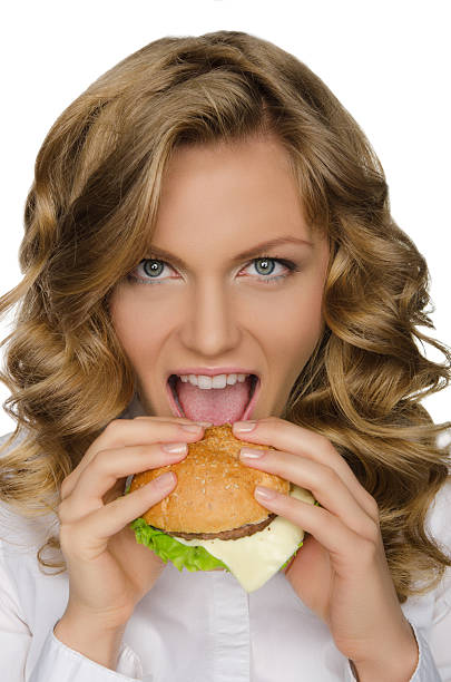 istock Beautiful young woman taking bite of hamburger 535812183