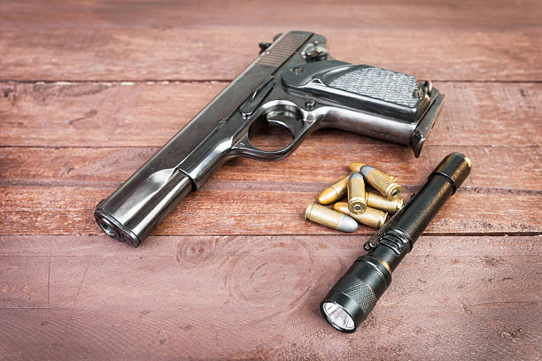 istock Semi-automatic 9mm gun and and tactical flashlight lying over on 535844029