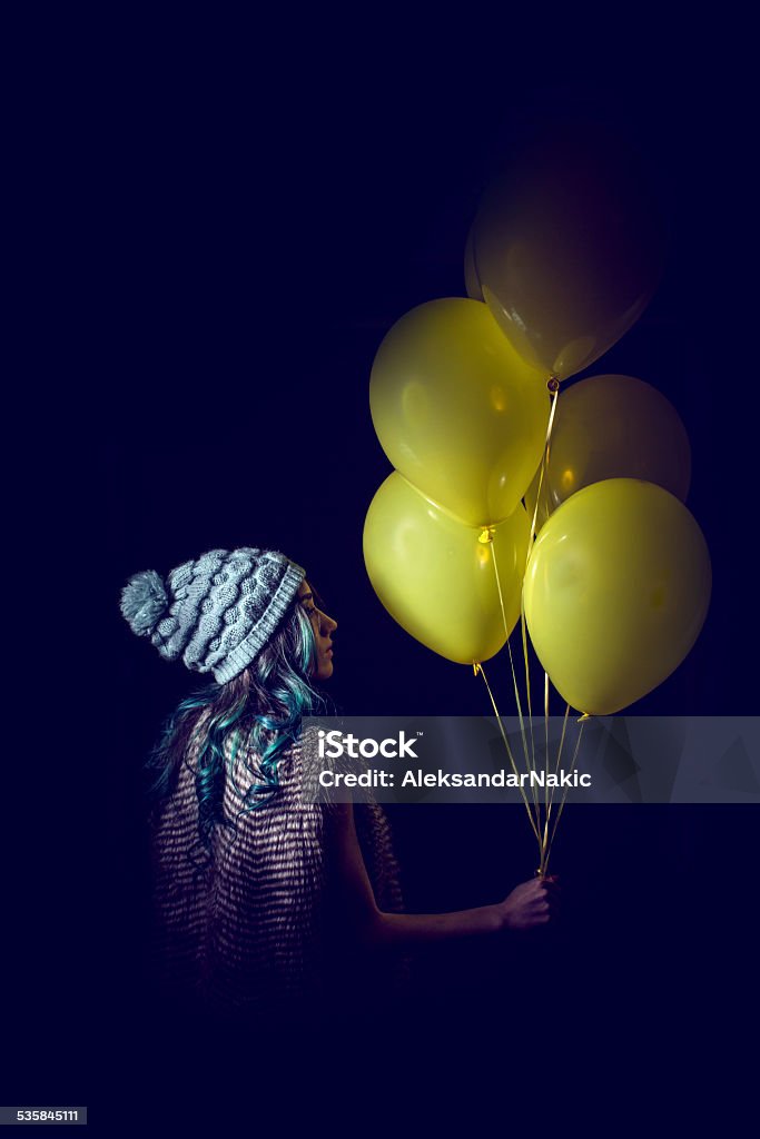 Take me to another place Fashion portrait of a young girl with a turquise dyed hair, holding yellow balloons Profile View Stock Photo