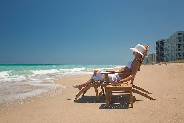 チーク材の椅子に座る女性のビーチでフロリダの - outdoor chair beach chair sarong ストックフォトと画像
