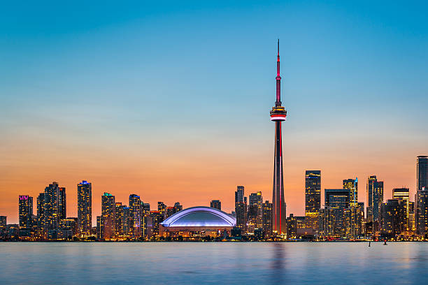 Toronto Skyline at twilight Skyline of Toronto over Ontario Lake at twilight canada stock pictures, royalty-free photos & images