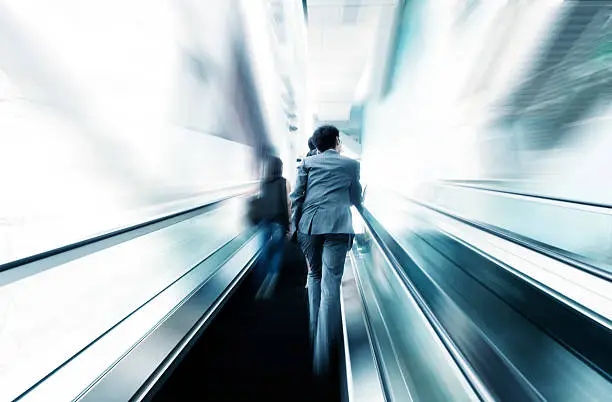 Photo of business people taking escalator blur motion,business on the move