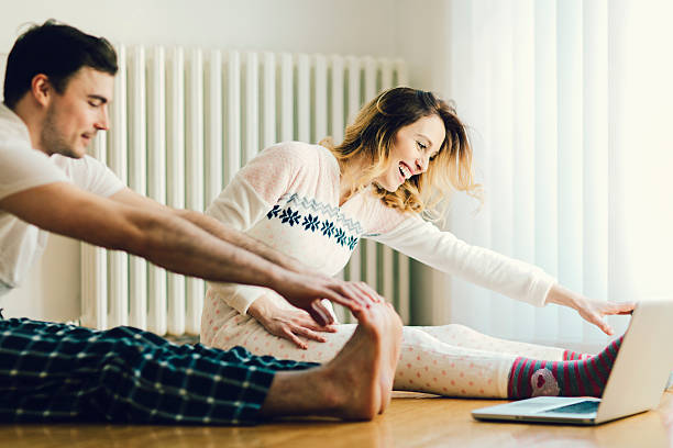 Couple Exercise in a living room with laptop. Cheerful couple having morning exercises in a living room, following instructions on laptop. new year resolution stock pictures, royalty-free photos & images