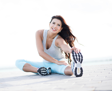 Athletic woman stretching her leg outdoors touching the tip of her toes