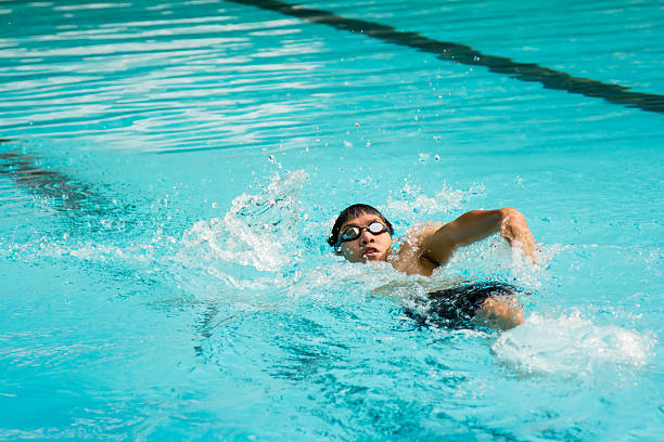 Giovane uomo nuotare in sul dorso in una piscina. - foto stock