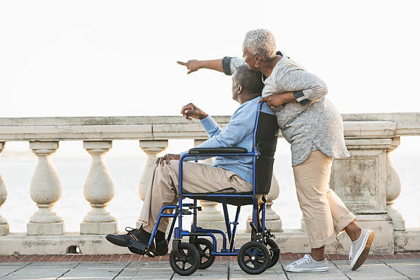 coppia senior con un uomo in sedia a rotelle - couple dependency standing men foto e immagini stock