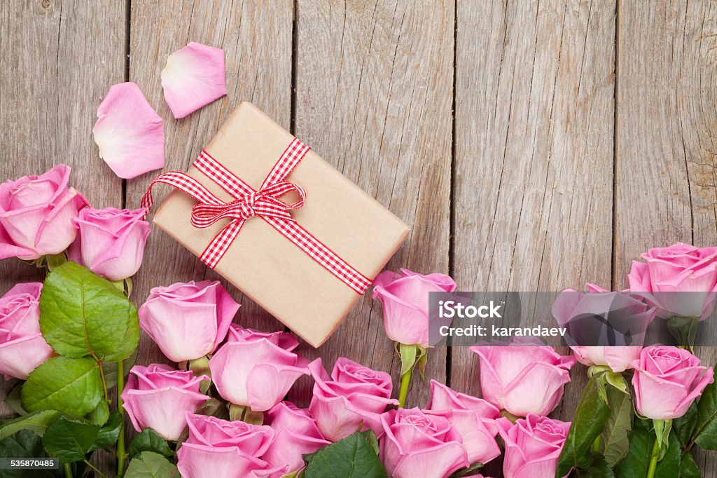 Valentines day background with pink roses over wooden table Valentines day background with pink roses over wooden table and gift box. Top view with copy space 2015 Stock Photo