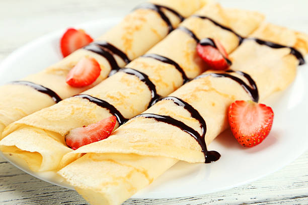 istock Rolled pancakes with strawberry on plate on white wooden background 535872947