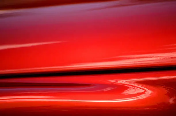 A close-up abstract photograph of a classic red sportscar