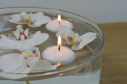 White and purple orchids with candles floating in a bowl of water