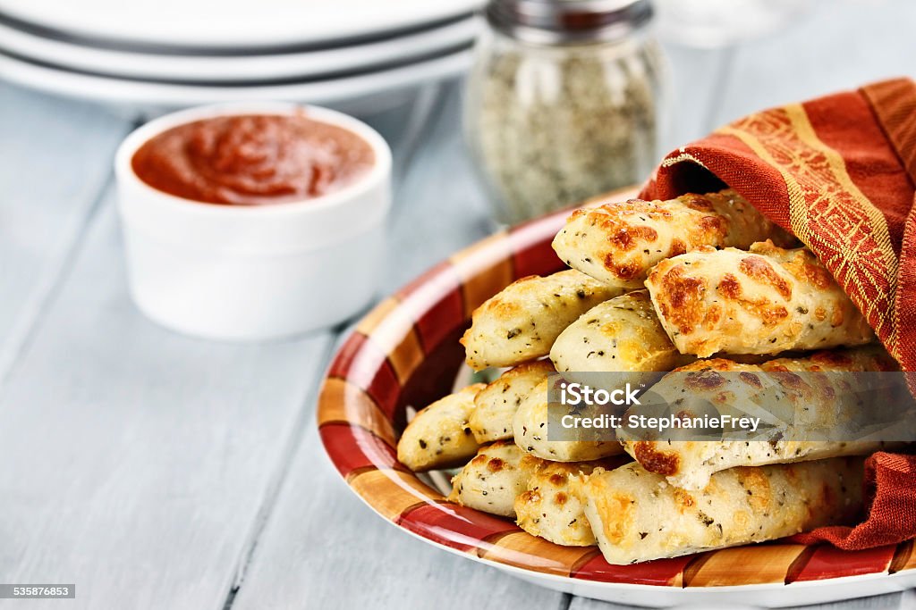 Cheesy Asiago Breadsticks and Marinara Sauce Fresh golden, cheesy breadsticks with marinara sauce and parmesan cheese in background. Shallow depth of field. Breadstick Stock Photo