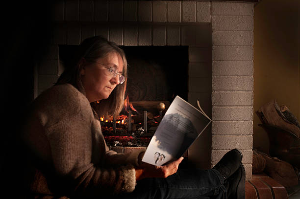 istock Woman reading book by fire 535888569