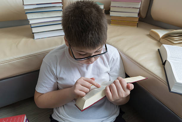istock Boy with glasses reading a book in  room 535891869
