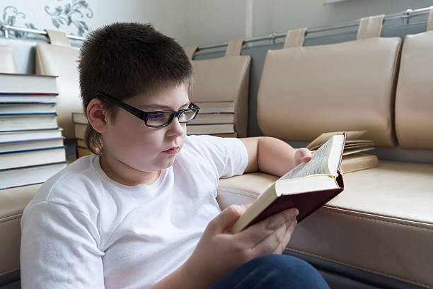 istock Boy with glasses reading a book in  room 535892065