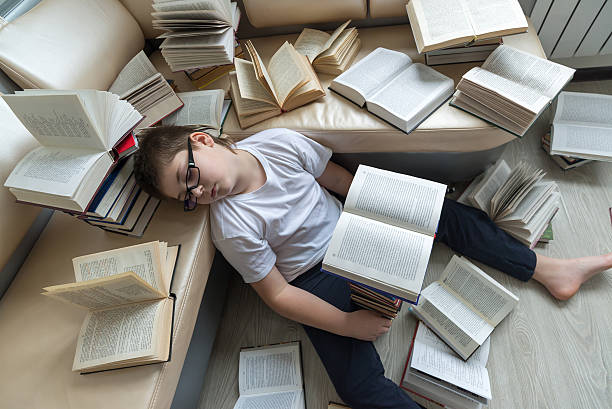 istock Tired boy sleeping surrounded by books in  room 535892285