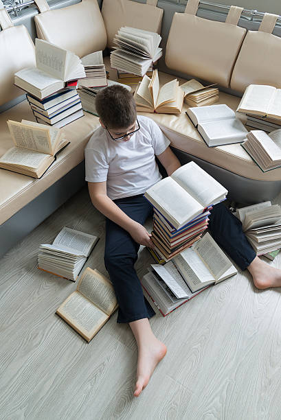 istock Tired boy sleeping surrounded by books in room 535892297