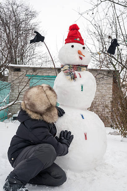 istock The boy in a fur hat around snowman 535895227