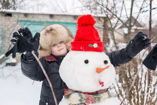 istock The boy in a fur hat around snowman 535895251