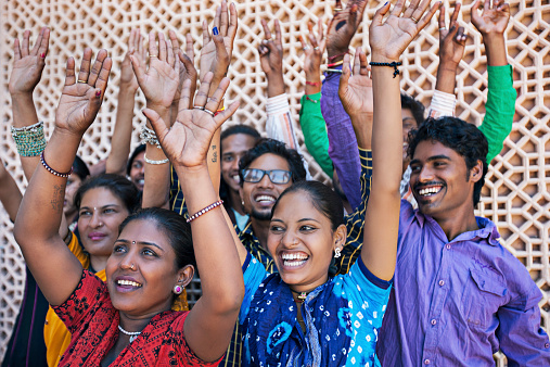 Group of Indian friends raising hands celebrating Holi.
