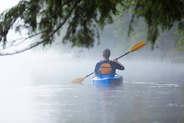 istock Senior man kayaking in morning mist 535913131