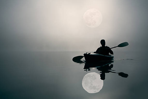 Adult man kayaking by the full moon light